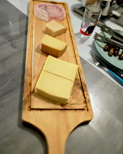 Planche à poignée finie, garnie de jambon et de fromage, sur une table de cuisine