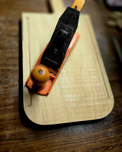 Rabot à main posé sur la même planche, une rainure creusée sur le pourtour