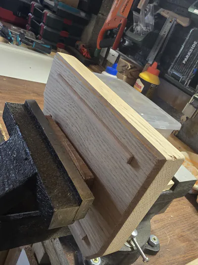 Planche serrée dans l'étau de l'établi, devant les rangements d'outils du sous-sol