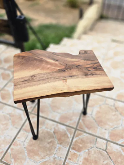 Guéridon à plateau de noyer à bord naturel, sur quatre pieds fins en métal noir