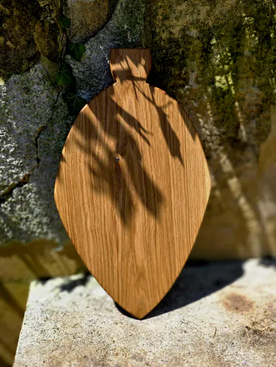 Planche en forme de feuille avec sa poignée, posée contre un muret de pierre au soleil