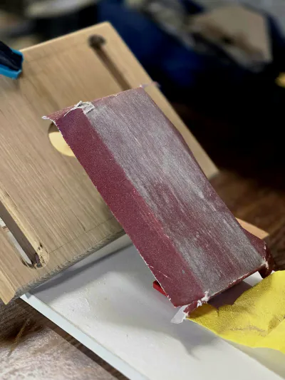 Cale à poncer posée sur une planche en cours de finition, sur l'établi