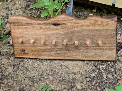 Porte-clés mural en bois foncé à bord naturel, huit chevilles en bois et logo gravé