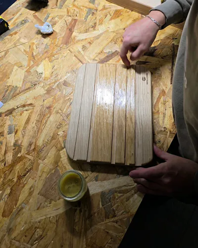 Planche en chêne à rainures, couverte d'une couche de baume brillante, le pot de baume posé à côté sur l'établi