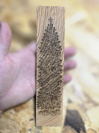 Marque-page en frêne olivier gravé d'un grand sapin décoré, tenu dans la main