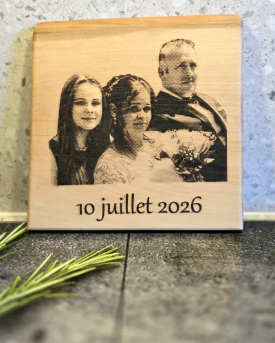 Plaque en bois clair gravée d'une photo de famille de trois personnes et de la date 10 juillet 2026