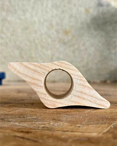 Bague de lecture en bois clair aux lignes asymétriques, posée sur une table en bois